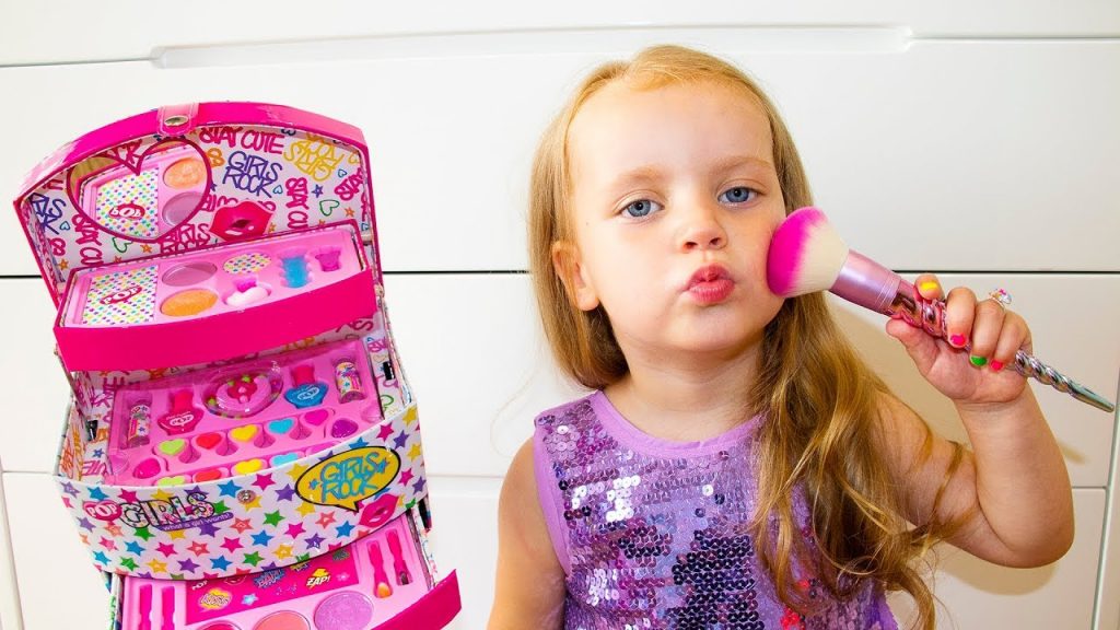 a cute little girl pouting her lips and brushing the makeup brush unto her face as she plays
